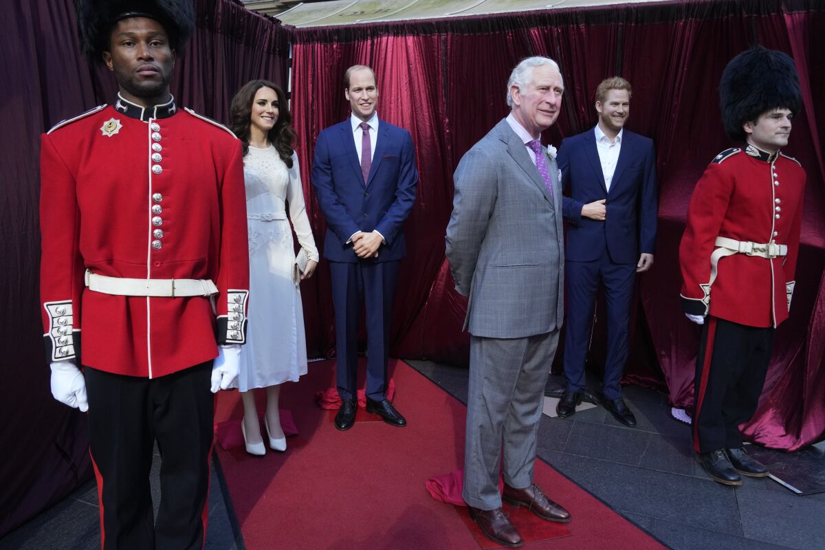 Hombres vestidos como guardias reales vigilan las figuras de cera del rey Carlos III, el príncipe Guillermo, Kate y el príncipe Harry.