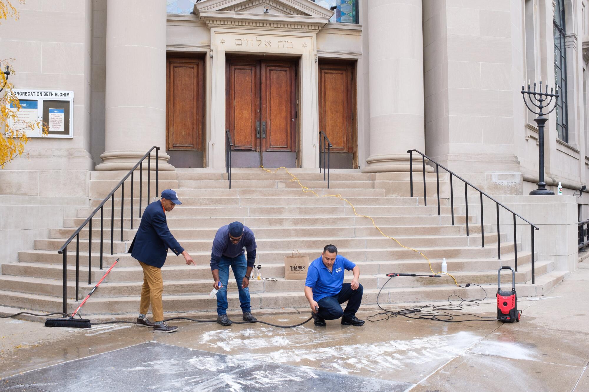 Los trabajadores limpian graffitis de una acera afuera de una sinagoga. 